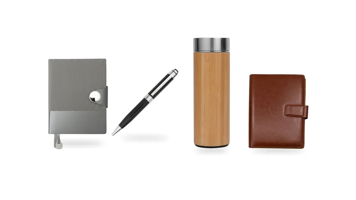 Grey notebook, black metal pen, bamboo insulated bottle and brown leather notebook on a white background.